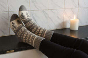 Ett par mönstrade raggsockor på ett stilrent stengolv – där funktionell design möter värmande komfort i ett modernt skandinaviskt hem.